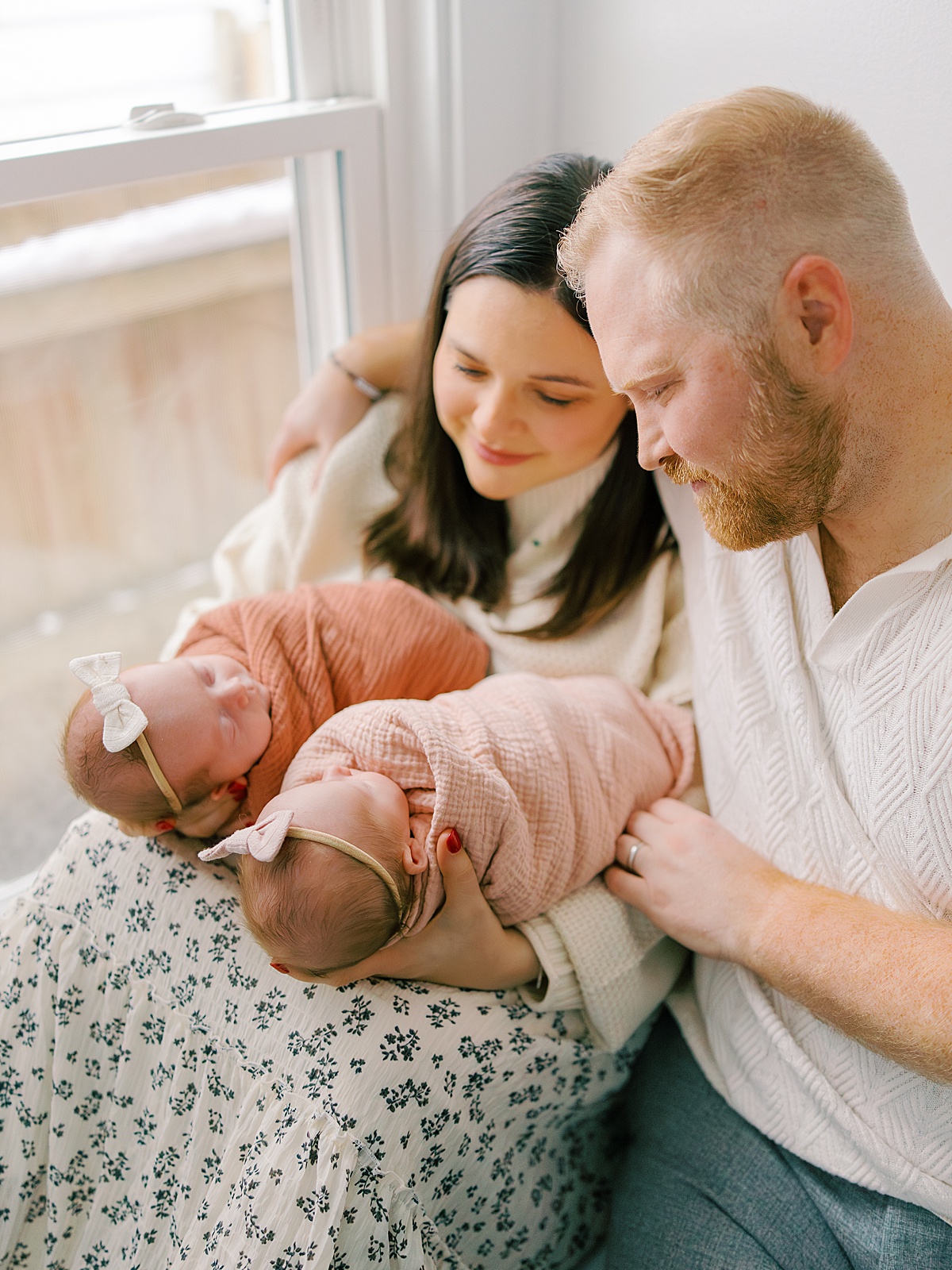 father and mother cozy up to their twin newborn girls on a cold winter day