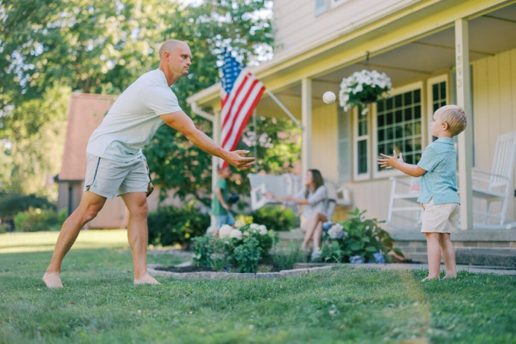 Backyard family session with father and son playing baseball together
